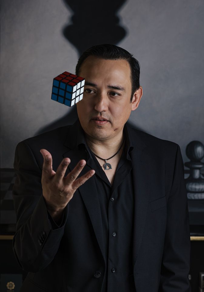 Retrato de Ale Estrello con un cubo Rubik suspendido en el aire
